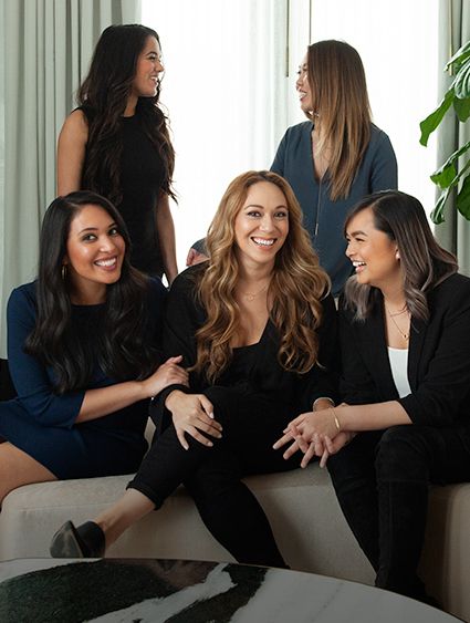 five women in business clothes sitting and talking
