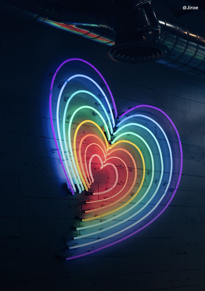 Nighttime view of a neon rainbow of lights forming a heart.