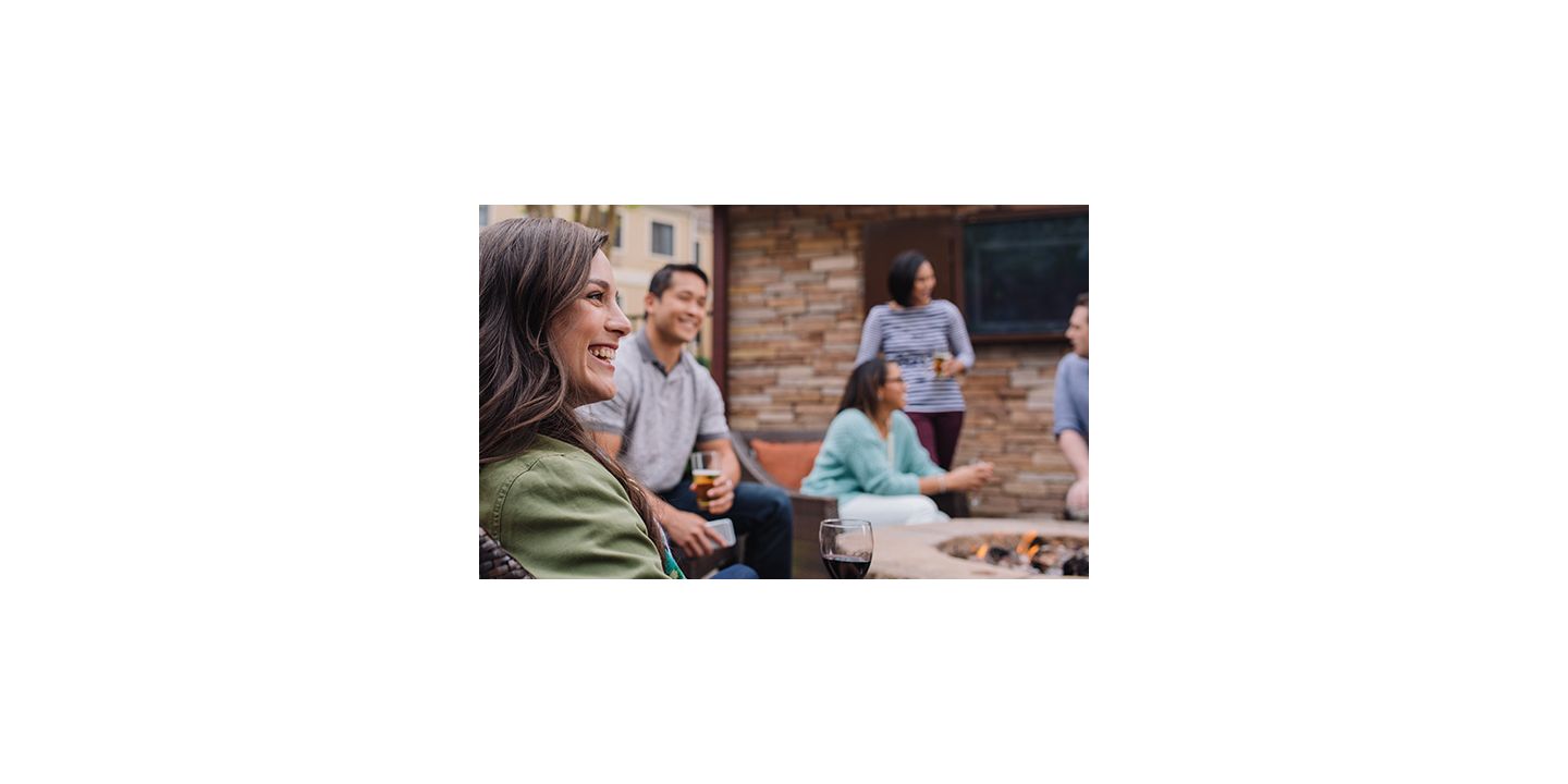 焚き火を囲み笑顔でお酒を飲む人々