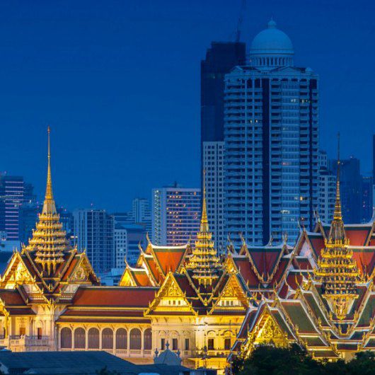 architettura storica con illuminazione color oro con cielo blu e grattacieli sullo sfondo