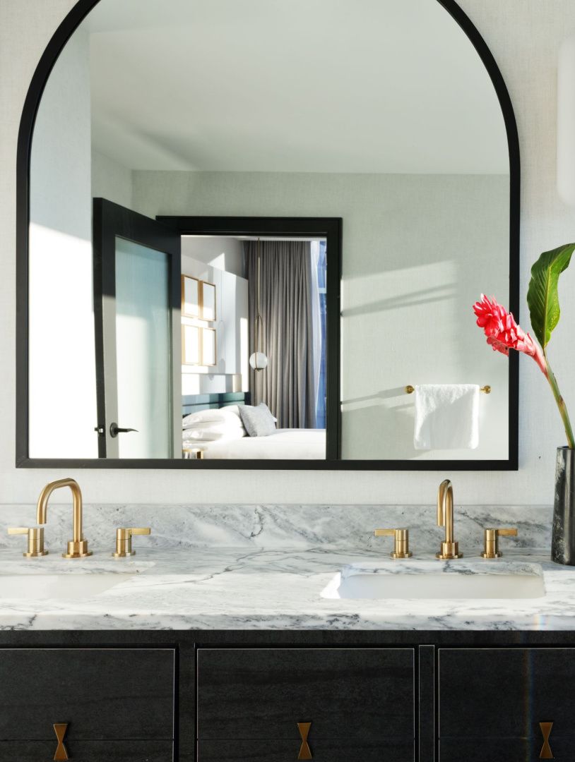 marble vanity with view of the crisp white guestbed in the mirror