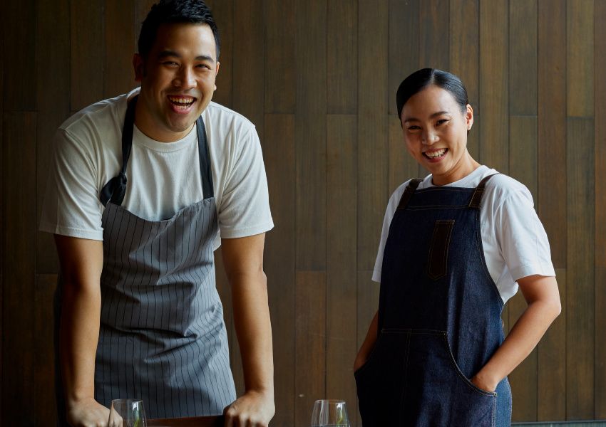 a man and a woman in blue aprons smiling 