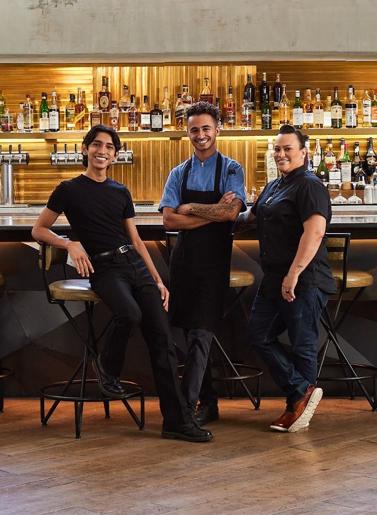 three people standing in front of a bar