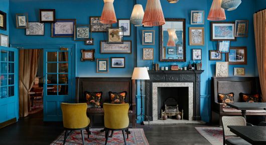Bright blue walled sitting room with various shaped and sized pictures 