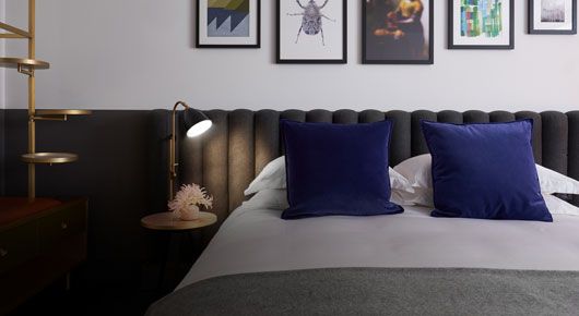 Hotel room with white and charcoal gray bed and bedding and deep blue accents