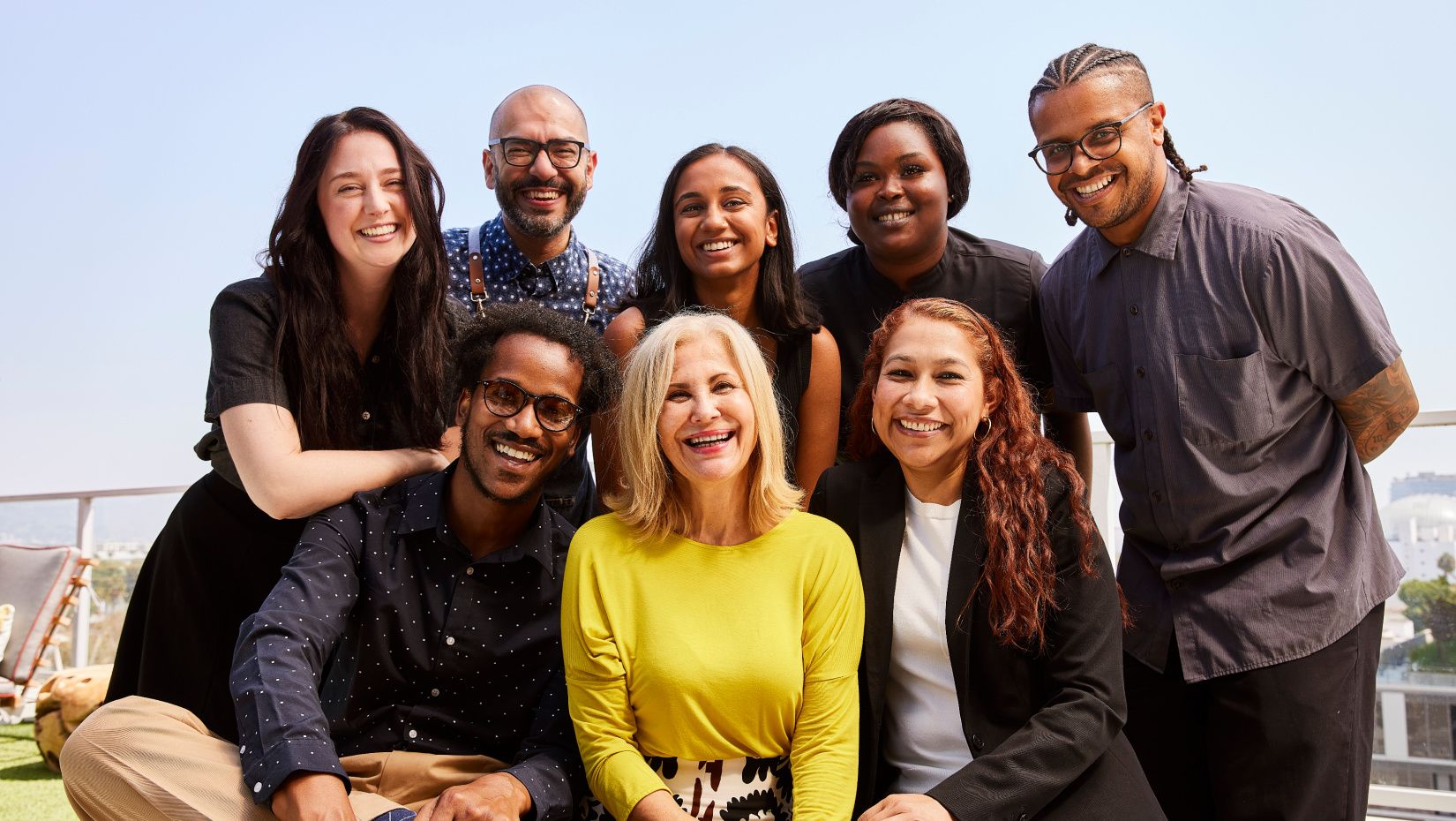 group of employees smiling warmly gathered outside