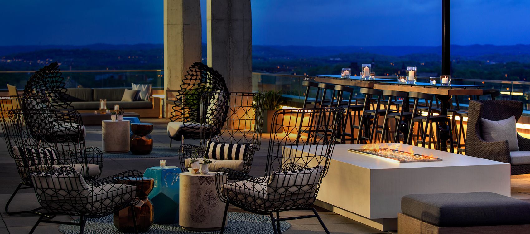 rooftop lounge seating with firepits and city views at night