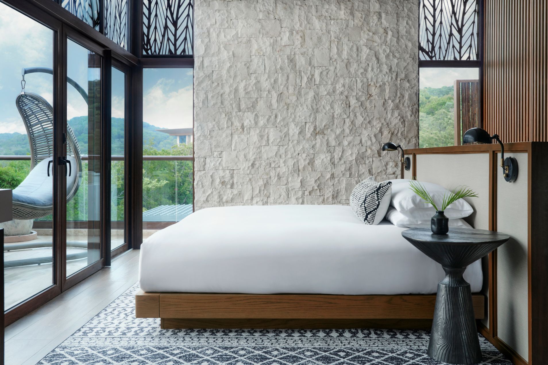 serene white bed in a corner room with views of lush island mountains and a balcony