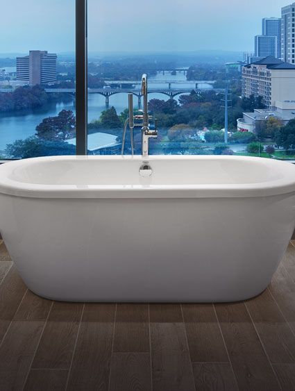 modern free standing tub next to glass wall overlooking a city