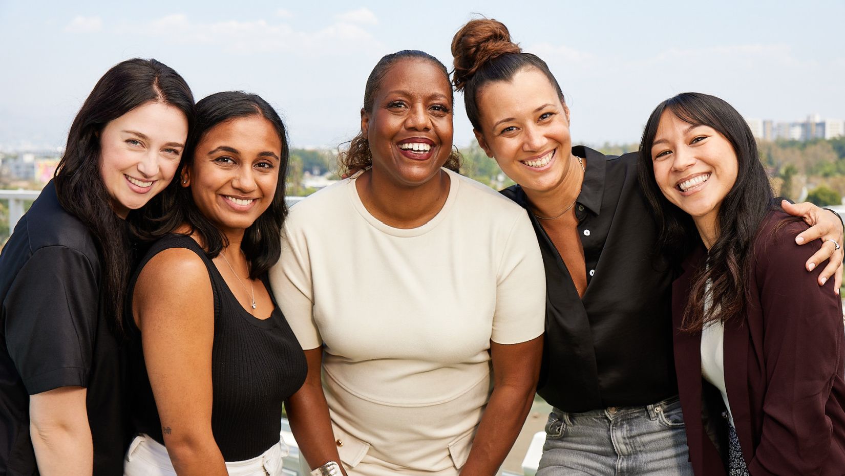 five women with arms around each other and smiling