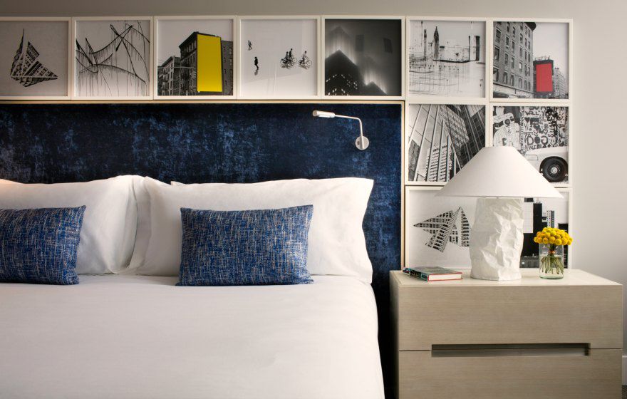 Guestroom headboard surrounded by black/white photographs and blue chenille pillows.