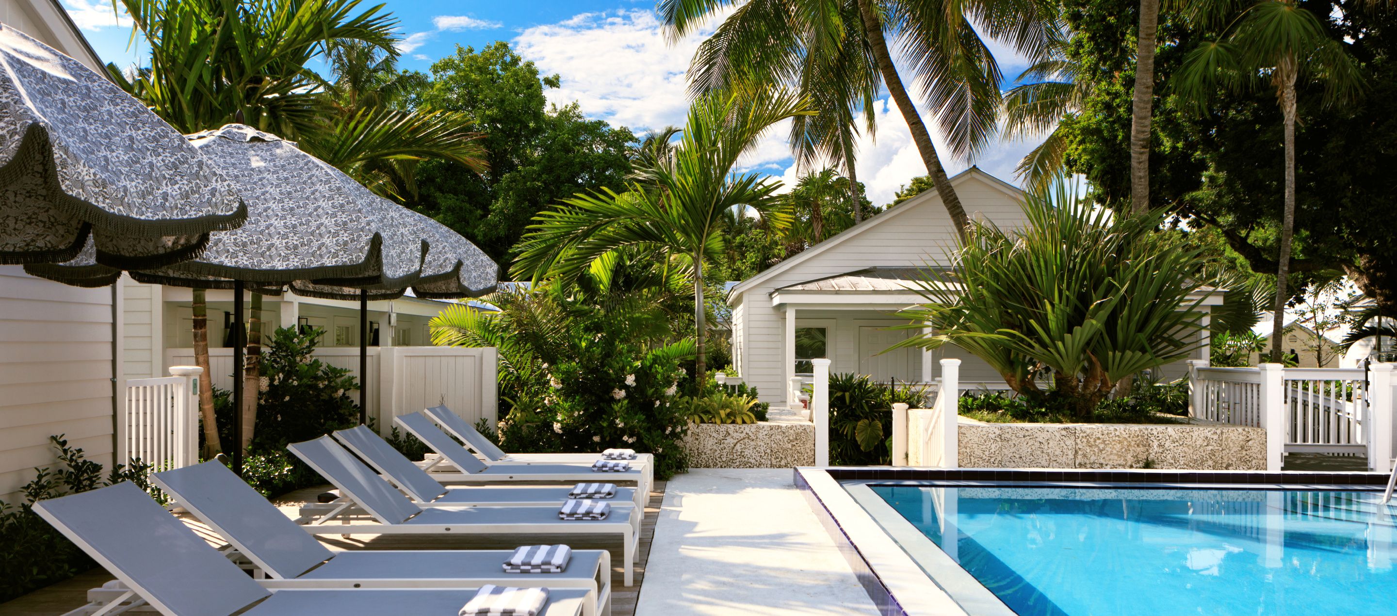 Sparkling outdoor pool and lounge chairs with umbrellas in key west