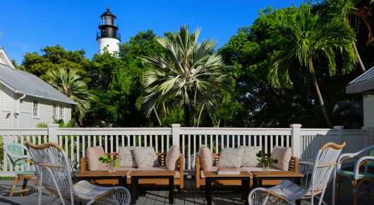Patio seating area with thick palm tree and top of lighthouse view