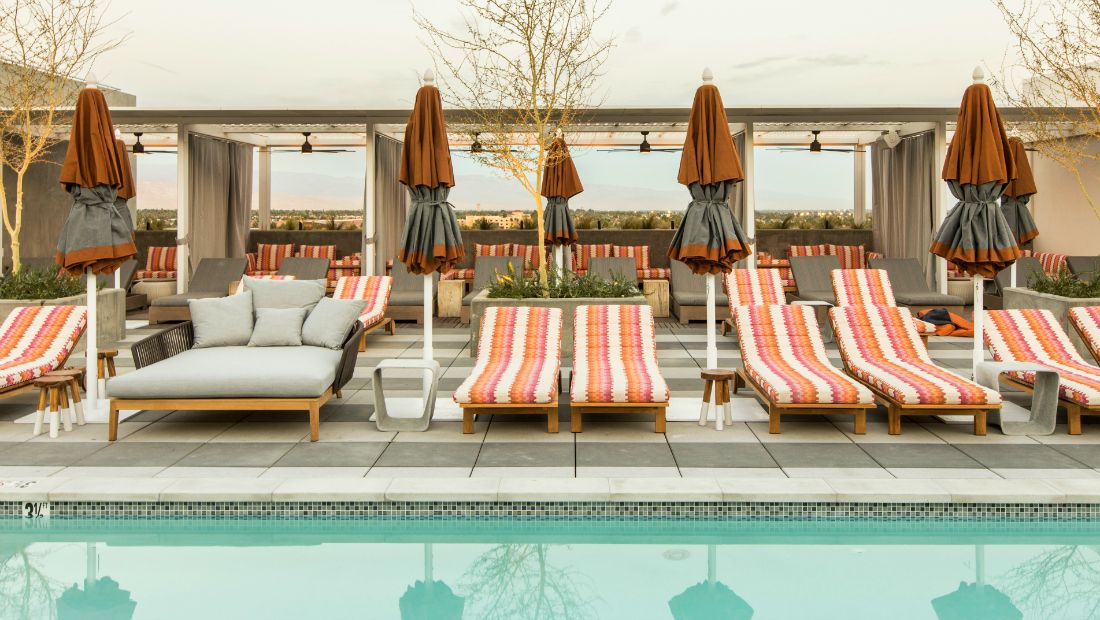 striped pillows on chaise lounges overlook aqua pool water