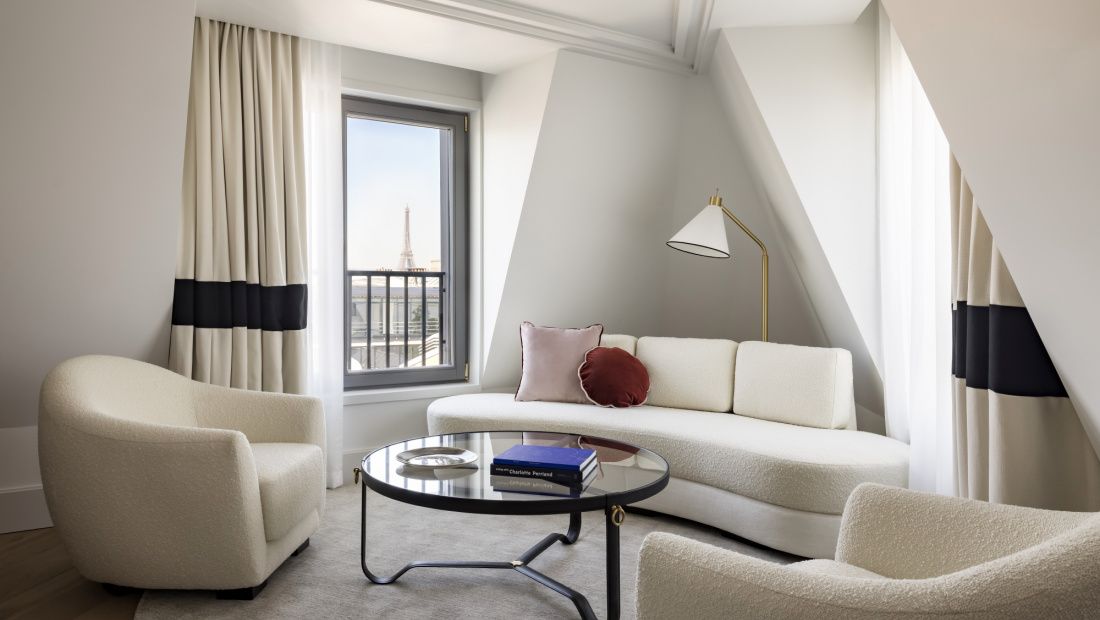 suite with white couch and chair and view of eiffel tower