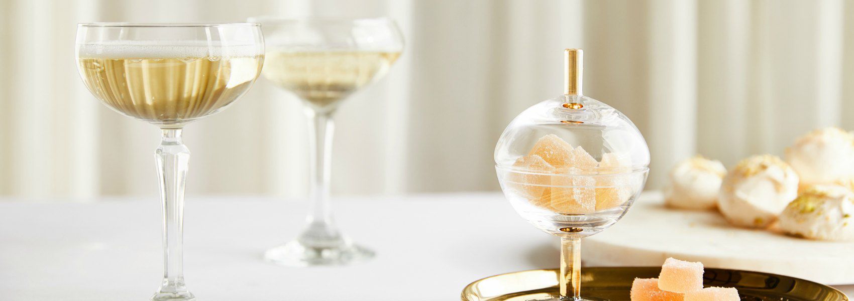close up of two champagne glasses filled with bubbly and a glass candy jar